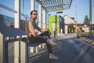 man wearing sunglasses sitting at bus stop during daytime